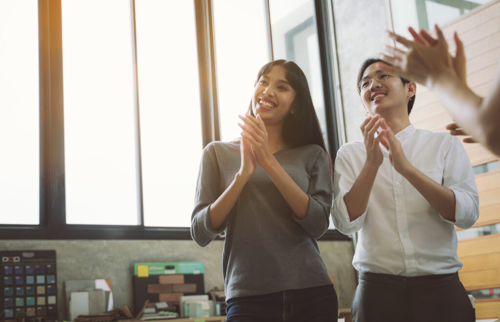 Employees applauding in a positive environment supported by real-time attendance data.