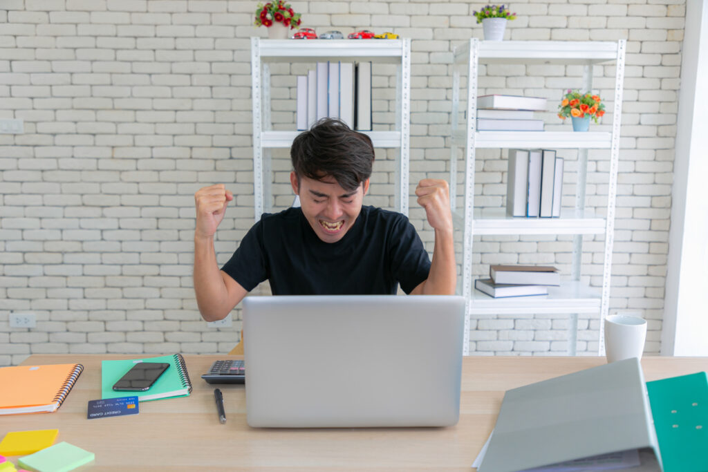 Excited employee celebrating at desk, showing the results of strong attendance management and workplace productivity.