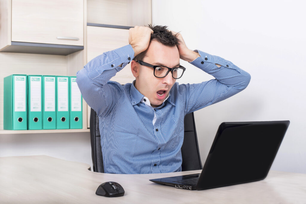 Shocked employee discovering a potential data breach on his laptop