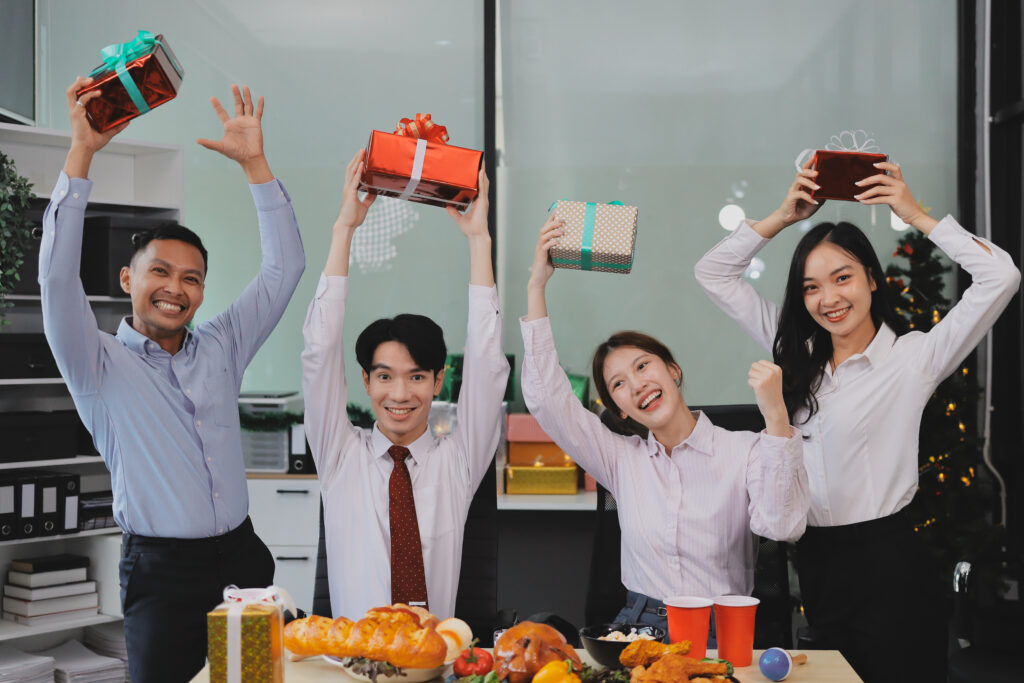 Happy employees holding gifts at a workplace celebration, illustrating HR in preventing workplace burnout through recognition.