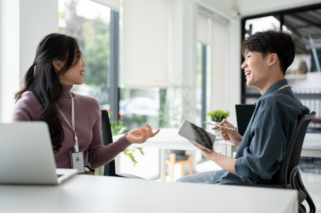 Two colleagues happily discussing work in a bright office