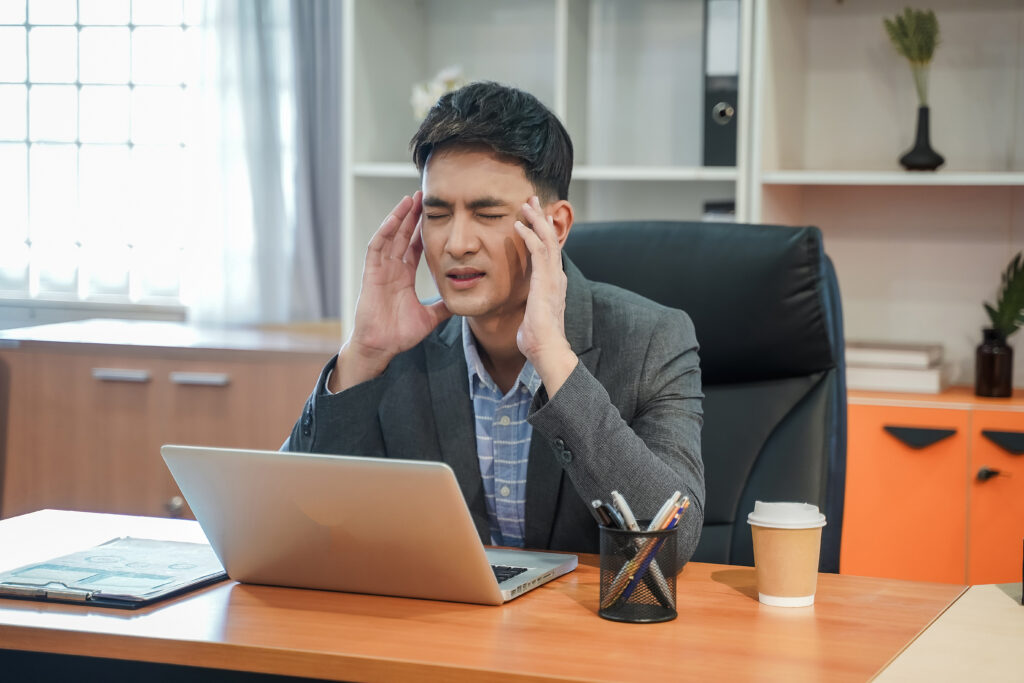 Stressed businessman holding his head while working on a laptop