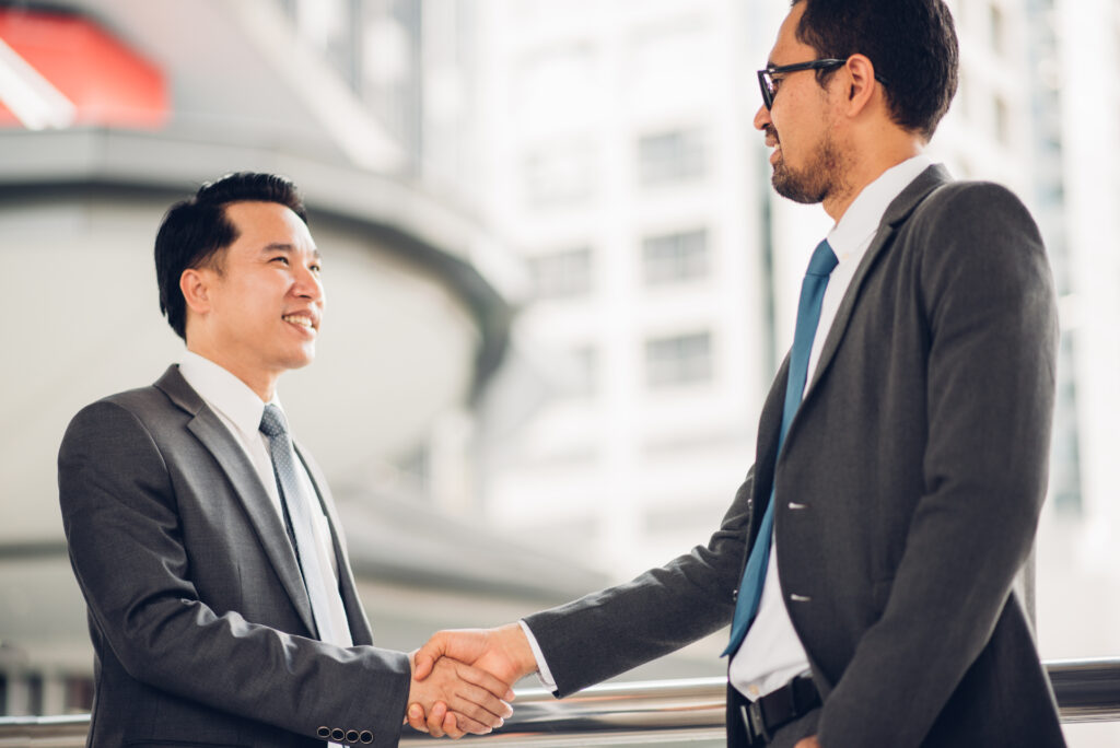 Businessmen shaking hands to symbolize the transition from Joint Management Body Malaysia to Management Corporation
