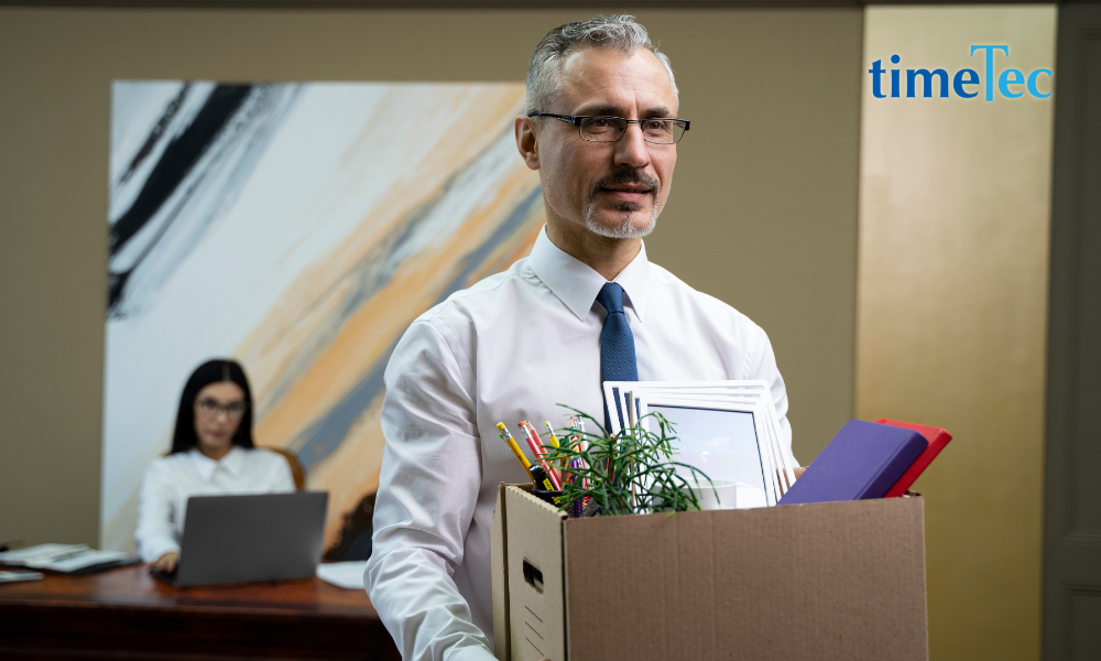 Man leaving office with a box of personal belongings after resignation
