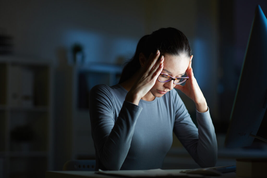 Stressed employee holding head while working at a laptop